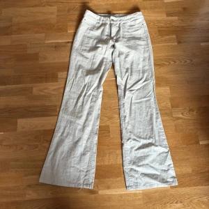 Beiga linnebyxor från Vila, storlek S - Snygga beiga linnebyxor från Vila i storlek S. Byxorna har en rak och lite vidare passform med bootcut och låg midja. Perfekta för en chill och stilren look, tillverkade i lite tjockare linne som passar grymt under varmare och kylligare dagar.