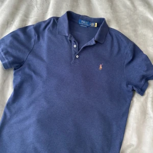 Blå pikétröja från Polo Ralph Lauren - Snygg blå pikétröja från Polo Ralph Lauren i 100% bomull. Topp skick nästan helt ny för endast 349kr! Skriv vid prisförslag eller funderingar! 