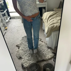 90's Flare jeans från H&M ljusblå - Säljer ett par 90's Flare jeans från H&M i snygg ljusblå tvätt. Jeansen har hög midja, klassisk femficksdesign och flare-ben för en retro vibe. Tillverkade i bomull med dragkedja och knapp framtill. Perfekta för dig som gillar vintageinspirerad stil.