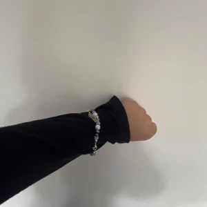 Färgglatt pärlarmband med silverdetalj - Unikt armband med mixade pärlor i blått, grönt, rött och lila samt en söt silverfärgad lövberlock. Armbandet har pärlor i olika former och storlekar, vilket ger en cool och personlig look. Perfekt accessoar för att lyfta din outfit. Vi har en utav denna sort.
