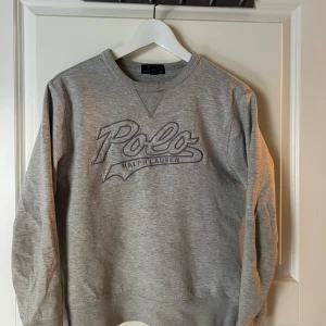 Grå sweatshirt från Polo Ralph Lauren - Snygg grå sweatshirt från Polo Ralph Lauren med broderad logga framtill. Klassisk rund halsringning och långa ärmar. Perfekt basic med stilren vibe, passar till jeans eller joggers. Mjuk och skön bomullsblandning.