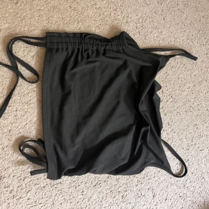 Siden Linné med knytband - Säljer en svart ärmlös linnetopp med smala axelband och knyt i sidorna. Toppen har en enkel och stilren design som passar perfekt till jeans eller kjol. 