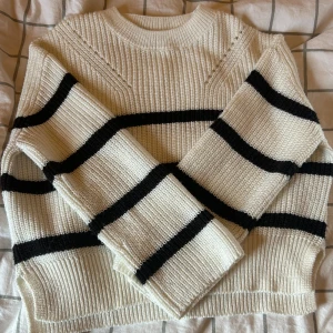 stickad tröja - Säljer en vit stickad tröja från Kappahl med svarta breda ränder. Tröjan har en loose passform, ribbade muddar och rund hals. Perfekt för dig som gillar en chill och trendig stil. Superenkel att matcha med jeans eller kjol. Stl 146/152, använd fåtal gånger.