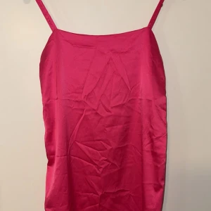 Rosa satin klänning från Zara - Säljer en snygg rosa kortklänning från Zara i satinliknande material. Klänningen har smala axelband och enkel, rak passform. Perfekt för dig som gillar en stilren look med lite extra glans. Superskön och lätt att styla med accessoarer. Finns hällor för snöre men tappat bort det tyvärr.