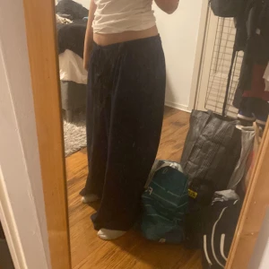 Mörkblå vida linnebyxor med snörning - Säljer ett par mörkblå linnebyxor med breda ben och skön loose fit. Byxorna har hög midja med snörning i midjan och sidfickor. Perfekta för chill dagar eller när du vill ha en avslappnad stil.