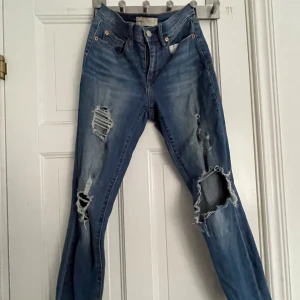 Blå ripped skinny jeans från Gap - Säljer ett par blå skinny jeans från Gap med rejält slitna och trasiga detaljer på båda benen. Modellen är True Skinny och jeansen har klassisk femficksdesign. Perfekta för dig som gillar en edgy och trendig streetstil.