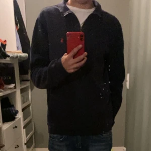 Mörkblå half zip tröja från Polo Ralph Lauren - Säljer en mörkblå långärmad tröja från Polo Ralph Lauren med half zip och klassisk krage. Tröjan har röd broderad logga på bröstet och är i mjuk bomull. Perfekt för dig som gillar stilren och enkel design.