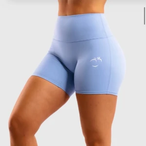 Blå träningstights shorts från Peach tights - Snygga ljusblå träningstights shorts från Peach med hög midja och tight passform. Tillverkade i stretchigt syntetmaterial som sitter perfekt under träningspasset. Diskret logga framtill och scrunch-detalj bak för extra shaping.