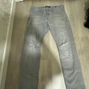 Grå raka jeansbyxor från scoth soda  - Snygga grå jeansbyxor från Scotch & Soda med klassisk femficksdesign och raka ben. Byxorna har normal passform och är tillverkade i mjukt jeanstyg. Perfekta för en clean och stilren look.