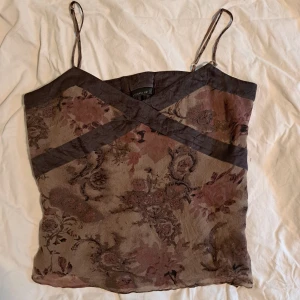 Blommig brun topp med tunna band - Supersnygg brun linnetopp från Stockh LM med tunna axelband och blommigt mönster. Toppen har en v-ringad skärning med mörkare bruna detaljer som korsar framtill. Linnet är lite stort för mig så håller därav in linnet där bak. Om ni vill se fler bilder eller har en fråga är det bara att höra av sig <3