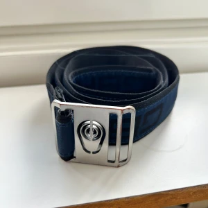 Sail Racing bälte - Snyggt blått bälte från Sail Racing med svart geometriskt mönster och coolt silverfärgat metallspänne med logotyp. Köpt på Stadium för 700kr