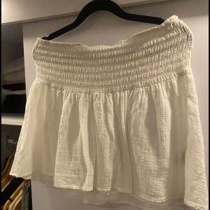 Vit kortkjol med smock i midjan - Superfin vit kortkjol med bred smock i midjan. Kjolen är gjord i ett tunt, strukturerat bomullstyg som känns perfekt för varma dagar.☀️⛱️Har gillat denna kjolen väldigt mycket, däremot har den varit lite för kort för mig. Den passar verkligen till allt och är jätte söt att ha på. ❤️😙
