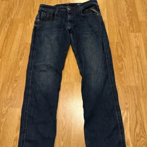 Replay Anbass slim jeans mörkblå 32 - Snygga mörkblå Replay Anbass jeans i slim fit med klassisk femficksdesign och diskreta slitningar. Jeansen har läderpatch bak, dragkedjegylf och är tillverkade i mjukt denimtyg som sitter skönt hela dagen. Är som nya knappt använda, pris inte hugget i sten skriv gärna förslag och om ni har frågor.
