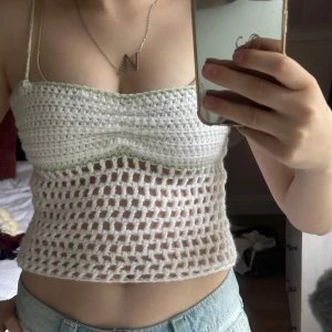 Virkad vit linnetopp med tunna band - Superfin virkad linnetopp i vitt med ljusgrön kant upptill. Toppen har tunna axelband och ett luftigt, hålmönstrat parti nedtill. Banden kan tas bort om man vill ha en vanlig tubtopp. Skriv för frågor!💗