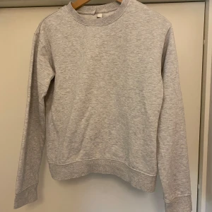 Ljusgrå sweatshirt från H&M, XS - Enkel och stilren ljusgrå sweatshirt från H&M i storlek XS. Tröjan har rund halsringning, långa ärmar och ribbade muddar vid ärmslut och nederkant. Perfekt för en chill och avslappnad look. Jättefint skick knappt använd. Skriv för fler frågor eller bilder osv. Läs bio. Kolla mina andra annonser också- pris går typ alltid att diskuteras!🙌😇