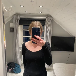 Svart ribbad långärmad topp H&M - Svart långärmad topp från H&M i ribbat material. Modellen har en djup, rundad ringning och sitter tight mot kroppen. Toppen är också väldigt skön i materialet!