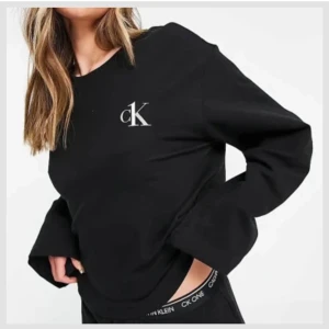 Svart Calvin Klein tröja med logga - Svart sweatshirt från Calvin Klein med CK-logga på bröstet. Tröjan har rund hals och breda långa armar. Loggan är hel men syns att tröjan är använd, i gott skick!