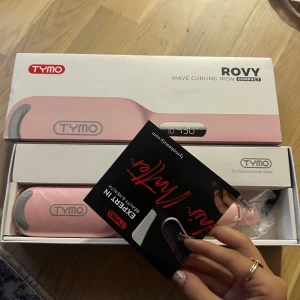 Tymo Rovy Wave Curling Iron Compact - Säljer en Tymo Rovy Wave Curling Iron Compact aldrig använd. Den har digital display, anti-scald design och W-formad struktur för djupare vågor. Perfekt för att skapa snygga beach waves snabbt och enkelt. Kommer i originalförpackning. Oöppnad 