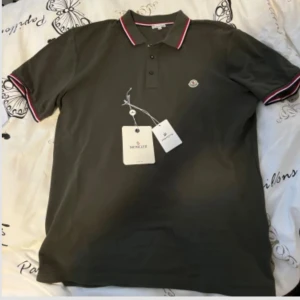 Moncler Pikétröja  - Säljer min moncler piké då den va för stor, står storlek XXL men upplever den mer som en L/XL.  Har inget kvitto kvar då den är köpt i butik, men äkthetsbevis finns genom taggen i tröjan och prislappen. Hör av dig om du har fler frågor☺️ 