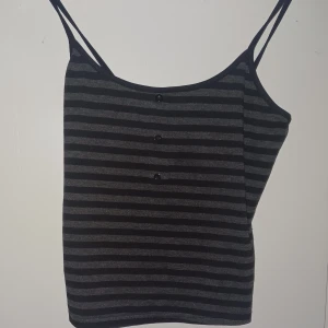 Svart och grå randig linnetopp -  Materialet känns mjukt men det e ett litet håll i sidan :( storleken e mellan M-L