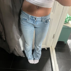 Ljusblå bootcut jeans  - Snygga ljusblå jeans från Gina Tricot med bootcut-modell och låg midja. Jeansen har klassiska fem fickor, slitningar vid knäna och coola detaljer på bakfickorna. Perfekta för dig som gillar en avslappnad och trendig stil💕