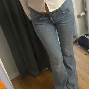 Ljusblå bootcut jeans - Säljer set med ett par ljusblå jeans med bootcut-modell och klassisk femficksdesign. Jeansen har låg midja och är tillverkade i mjukt denimtyg som sitter snyggt över höfterna och släpper ut vid benen. Perfekta för en avslappnad och trendig look. Och en tröja med fler rosetter vilket ger stilig stil och matchande set. Du får både och för 750kr byxorna köptes för 699kr och tröjan 209kr tröjan är helt ny och byxorna är använda 3 gånger: Byxor är i storlek 34 och tröjan är i storlek S