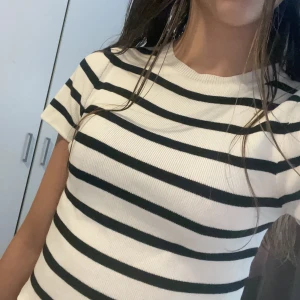Randig ribbad topp i svart och vitt - Säljer en ribbad topp med svarta och vita horisontella ränder. Modellen är croppad med korta ärmar och rund halsringning. Tyvärr så vet jag inte vilket märke eller storlek💕 men passar för 152/158 och xs/s då de är de storlek jag har på kläder🙌🏼💕