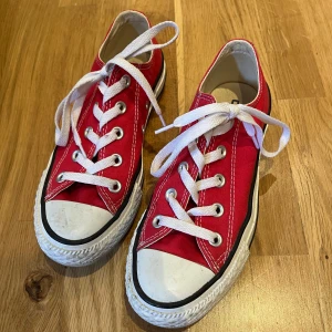 Röda Converse All Star sneakers - Klassiska röda Converse All Star sneakers med vit tå, vita snören och sula. Lågt skaft och tydliga kontrastsömmar. Ovandel i canvas och sula i gummi. Perfekta för en avslappnad och cool stil. 