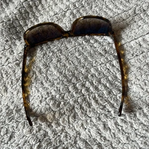 Ray-Ban Wayfarer brunmelerade solglasögon - Snygga Ray-Ban Wayfarer solglasögon med brunmelerad båge i klassisk modell. Glasen är mörka och bågen har en cool sköldpaddsmönstrad look. Perfekta för att lyfta din stil under soliga dagar.