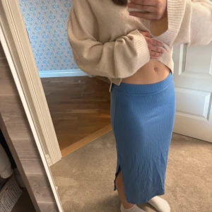 Blå ribbad långkjol från Kappahl - Säljer en blå ribbad långkjol från Kappahl i storlek XS. Kjolen har en tight passform men är stretchig, slits på sidan och är gjord i en mjuk mix av bomull och polyester. Perfekt för dig som gillar en enkel men snygg look.