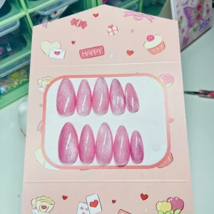 Rosa glittriga lösnaglar i almondform - Säljer ett set med 10 stycken lösnaglar i en snygg almondform. Naglarna är glansiga och har en skimrande rosa färg med glittereffekt. Perfekt för dig som vill ha en söt och trendig look. Kommer i en gullig förpackning med hjärtan och cupcakes.