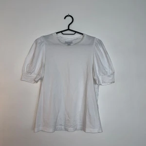Vit blus med puffärm från H&M - Säljer en stilren vit t-shirt med puffärmar från AWARE BY VERO MODA. 