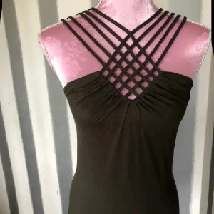 Olivgrön linne med unika axelband - Supersnygg olivgrön linne med flera smala axelband som korsas i ett coolt mönster framtill. Toppen  har en tight passform och är ärmlös, perfekt för dig som vill sticka ut med en stilren men ändå unik look.