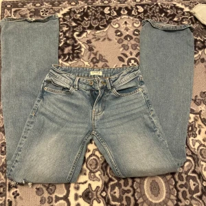 Ljusblå ripped jeans från Lindex - Säljer ett par ljusblå jeans från Lindex med snygga slitningar och trasiga detaljer på benen. Klassisk femficksmodell med dragkedja och knapp. Jeansen har en bootcut passform och är tillverkade i bomull. Perfekta för en avslappnad och trendig look.