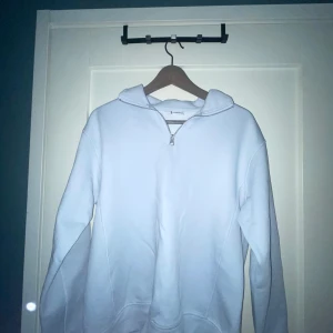 Vit hoodie med half zip från Zara - Vit hoodie från Zara i storlek M med huva och half zip-dragkedja framtill. Tröjan har långa ärmar och är gjord i mjuk bomull, perfekt för en chill och avslappnad stil. Enkel och clean design som funkar till det mesta.