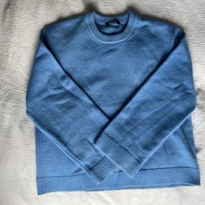 Blå stickad tröja från Gina Tricot - Superfin blå stickad tröja från Gina Tricot med rund halsringning och breda muddar vid ärmslut och nederkant.