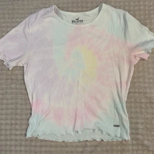 Topp från Hollister - Superfin ribbad topp från Hollister i pastellfärgat tie-dye mönster med vågiga kanter. Inte använd på flera år. 