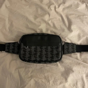 Lacoste väska - Säljer en riktigt snygg Lacoste väska äkta solklart och är i väldigt bra skick, en liten defekt på märket som har tappat lite färg bara