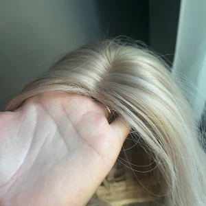 Lång blond peruk med mittbena - Snygg lång peruk i kall blond nyans med mittbena. Håret är rakt och har naturlig glans. Insidan har justerbara band och spets för bra passform. Perfekt för att byta stil snabbt och enkelt.