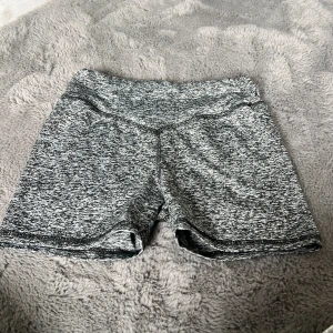 Gråmelerade träningstights shorts SHEIN - Gråmelerade shorts från SHEIN i stretchigt material, perfekta för träning eller sport. De har en bekväm midja och sitter tight mot kroppen. Snyggt mönster i svart och grått som ger en sportig vibe.