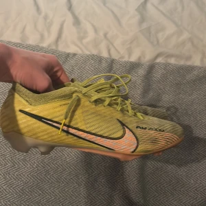 Gula Nike mercurial vapor 15 - Säljer ett par gula Nike fotbollsskor. Modellen är mercurial vapor 15. Skorna har ett ganska bra skick 7/10. Inga defekter. Dobbarna är lite slitna men går helt klart att spela med. Skriv vid frågor