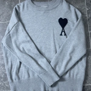 Grå stickad tröja från Ami - Ami Paris tröja. Använd ett fåtal gånger, jättebra skick. Påse medföljer 