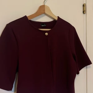 Vinröd kofta från Gina Tricot - Snygg vinröd kofta från Gina Tricot med en stilren knappdetalj framtill. Den har trekvartsärmar och en snygg design som passar perfekt för en classy look❣️ endast använd fåtal gånger