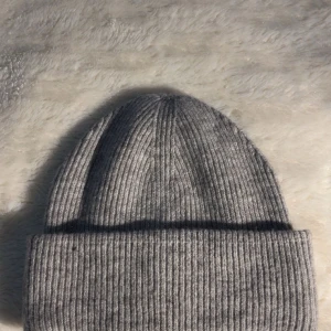 Grå ribbad mössa från Lager 157 - Snygg och enkel grå ribbad mössa från Lager 157. Perfekt för kyliga dagar och ger en stilren look. Tillverkad i ett mjukt och bekvämt material.