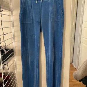 Blå mjukisbyxor från Juicy Couture - Snygga blå mjukisbyxor från Juicy Couture med en avslappnad passform. Byxorna har praktiska fickor både fram och bak, samt en dragsko i midjan för justerbar passform. Perfekta för en bekväm och stilren look. Även u bra skick kan finnas någon fläck men ska försöka få bort de mesta. Pris kan diskuteras.