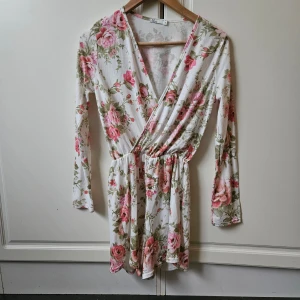 V-ringad playsuit  - V-ringad blommig ny playsuit med långa ärmar och resår I midjan.  Nypris 399 kr 