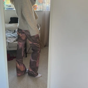 Färgglada byxor med mönster - Snygga byxor med ett unikt färgmönster i rosa och bruna toner. Byxorna har en rak passform och är perfekta för att sticka ut. De är tillverkade i ett bekvämt material som ger en skön känsla hela dagen.