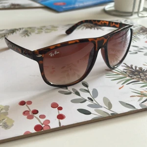 Leopardmönstrade solglasögon från Ray-Ban - Snygga solglasögon från Ray-Ban med leopardmönster. De har en klassisk form och bruna tonade glas. Perfekta för att ge en cool touch till din stil.