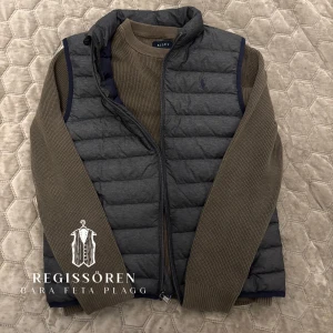 Grå dunväst från Polo Ralph Lauren - Snygg grå dunväst från Polo Ralph Lauren med dragkedja och två fickor framtill. Perfekt för lager-på-lager under kyliga dagar. Diskret logga på bröstet ger en stilren look. Storlek S