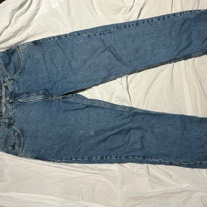 Blå vintage jeans från Rifle - Säljer ett par klassiska blå jeans från Rifle. De har en rak passform och är tillverkade i slitstarkt denim. Arbetsbyxor så finns vit färg stänk dem så lägger till karaktär. Passar för längre ben